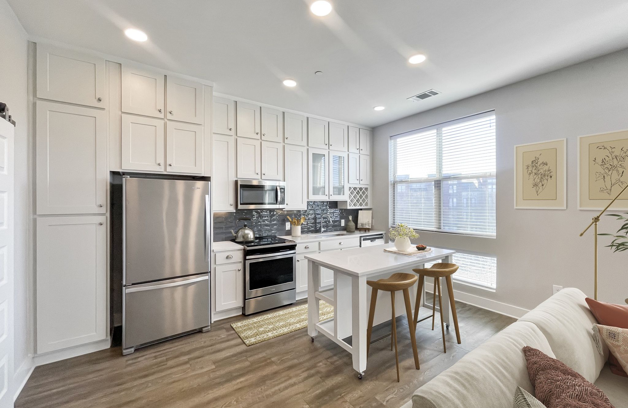 Studio apartment kitchen with floor-to-ceiling cabinets, stainless steel appliances, and floating island