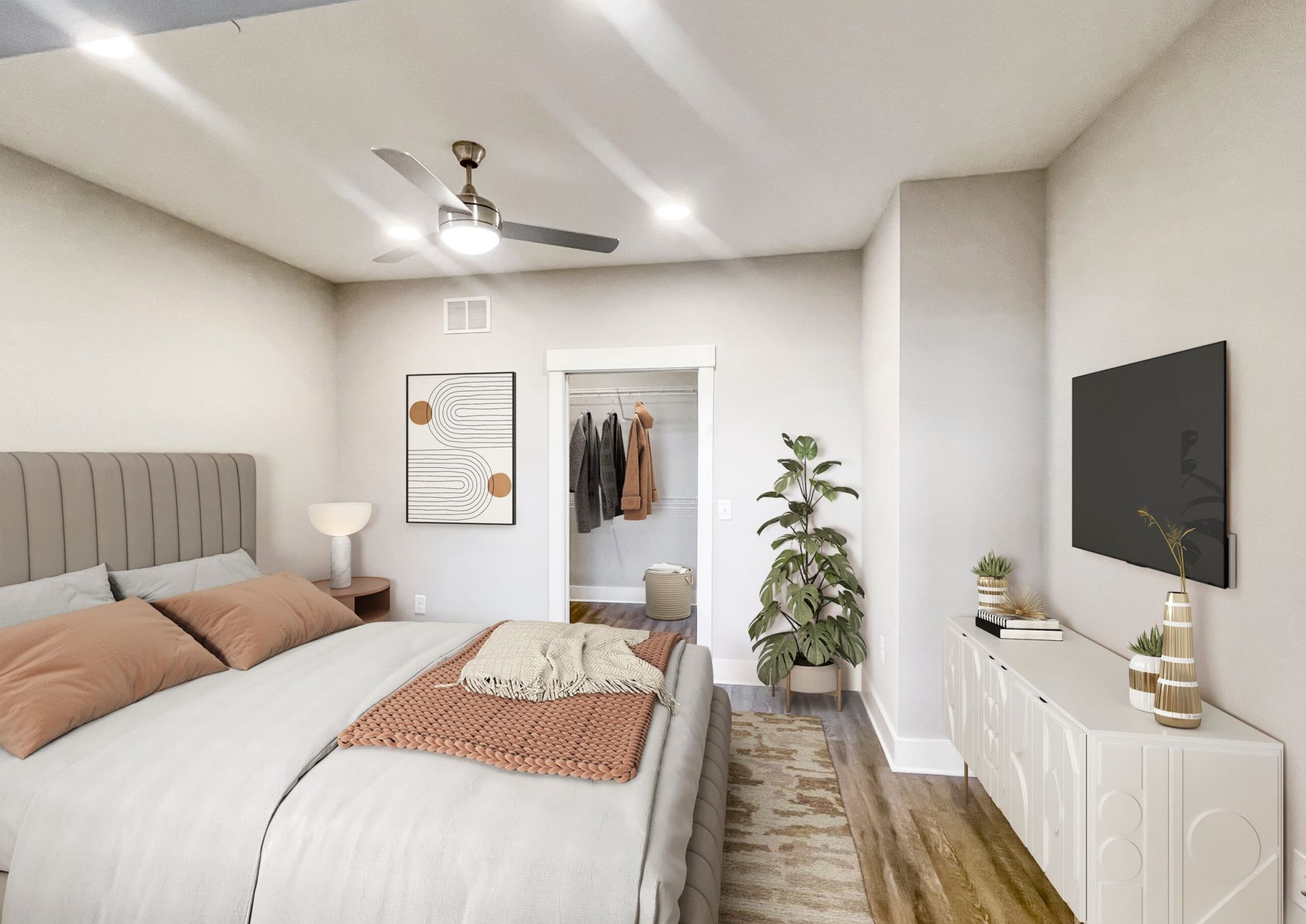 Apartment bedroom with large bed, indoor plant, closet, and ceiling fan