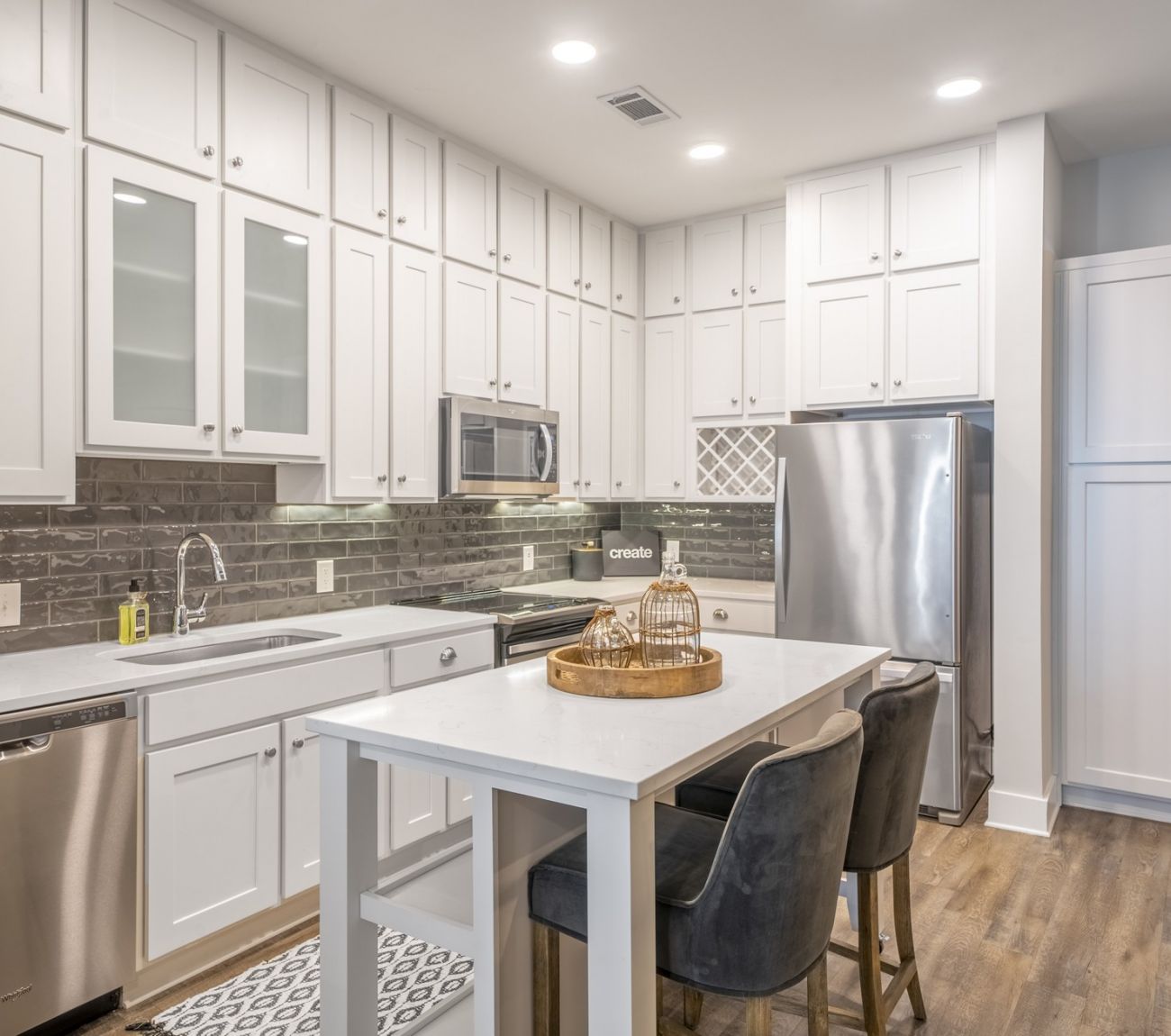 Kitchen with floor-to-ceiling designer cabinets, stainless steel appliances, and floating island at McEwen Northside Apartments