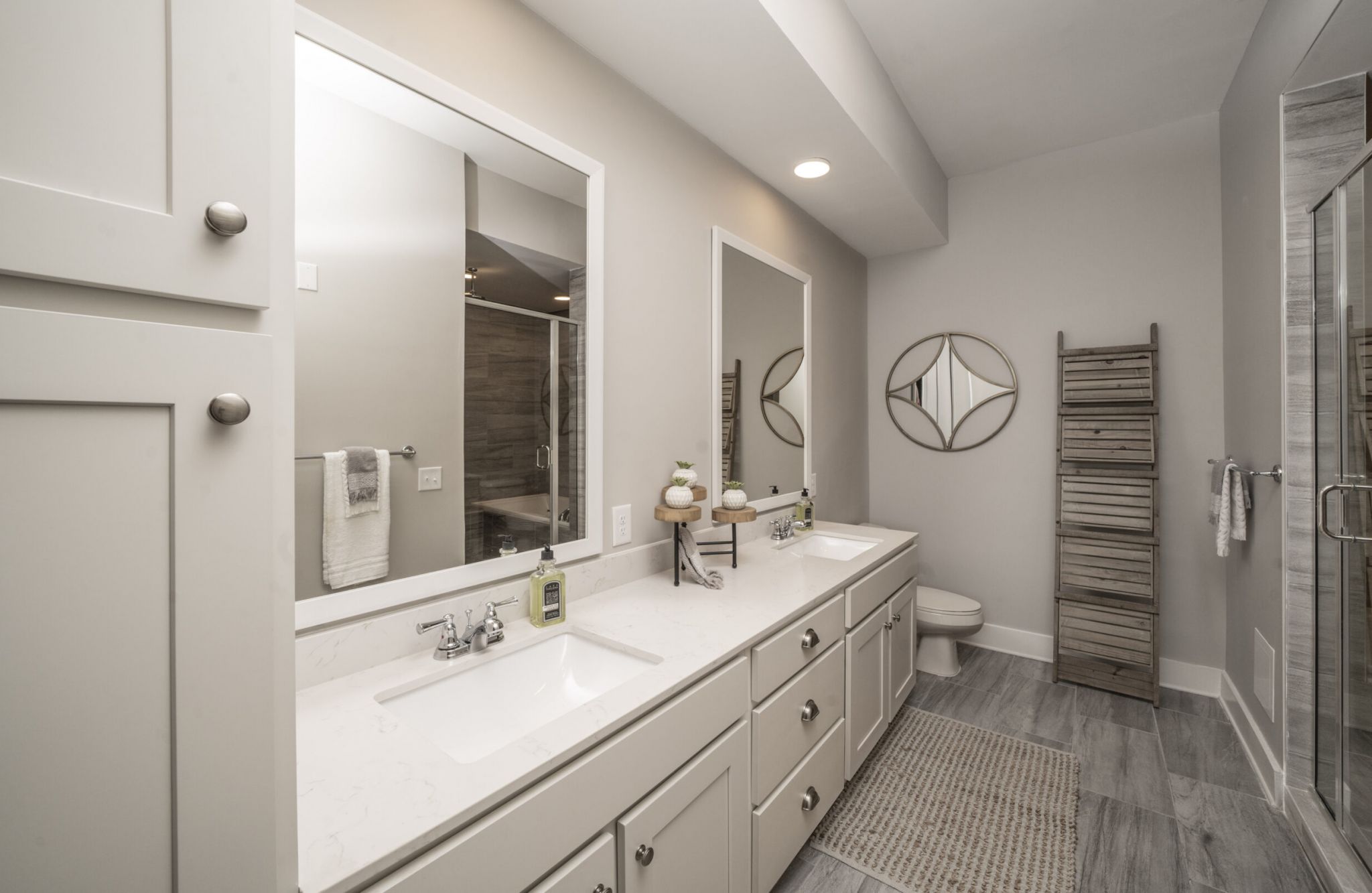 A beautiful apartment bedroom with double vanities and a glass enclosed shower
