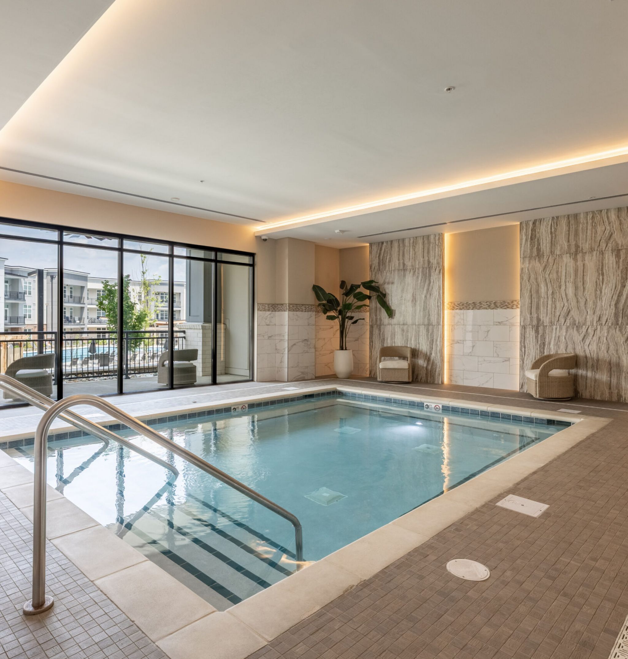 Beautiful view of McEwen Northside Apartment's luxury outdoor pool at night with seating and umbrellas