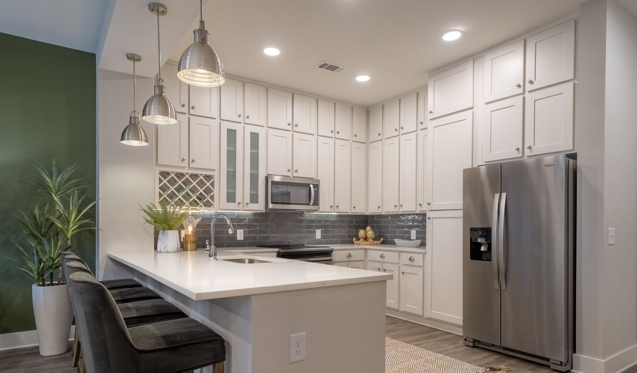 Studio apartment kitchen with floor-to-ceiling cabinets, stainless steel appliances, and floating island