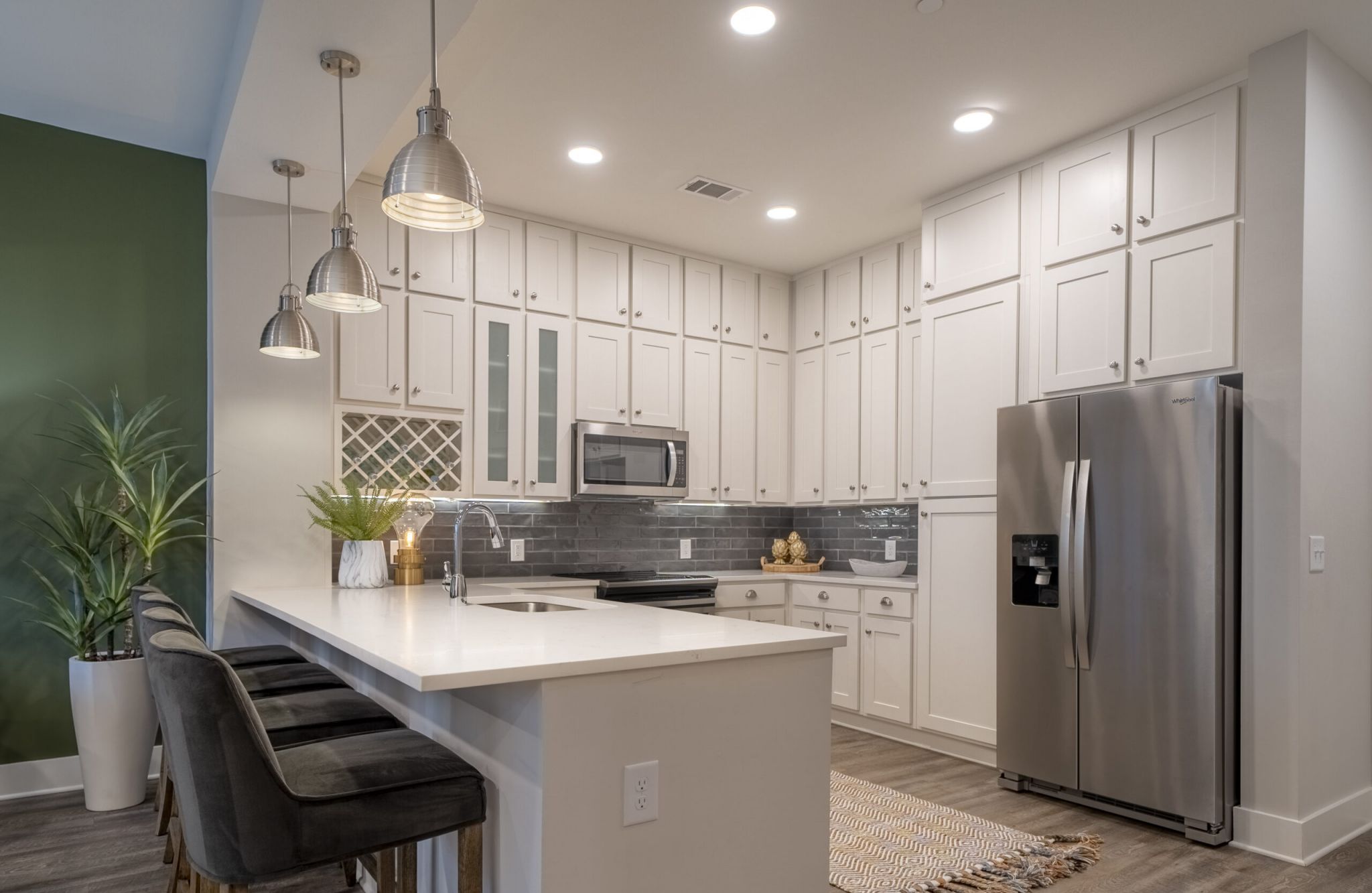 Studio apartment kitchen with floor-to-ceiling cabinets, stainless steel appliances, and floating island