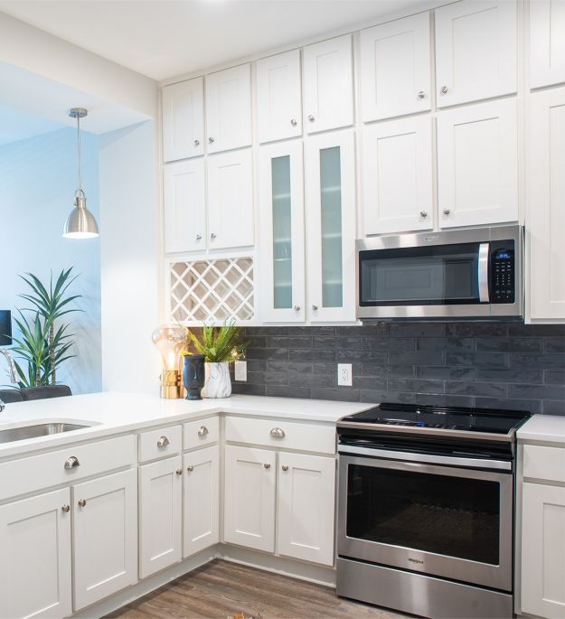 High-end apartment kitchen with floor to ceiling cabinets, stainless steel appliances, pendant lighting, and built-in wine storage