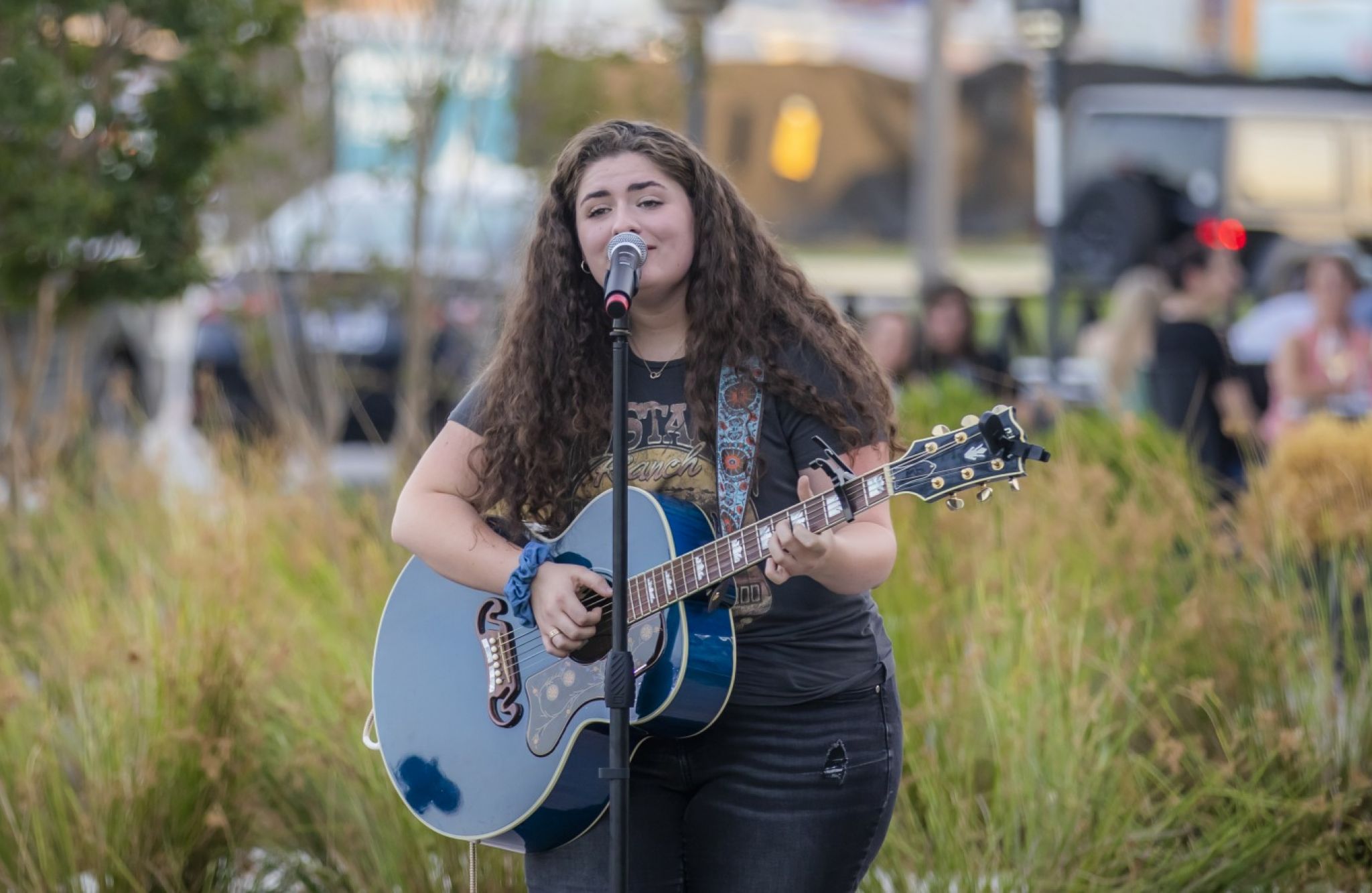 Girl singing into microphone while playing guitar